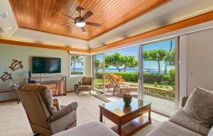 a living room with a ceiling fan and a view of the ocean at Puunoa Beach Estate in Lahaina