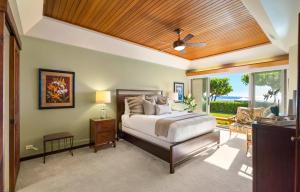 a bedroom with a bed and a large window at Puunoa Beach Estate in Lahaina