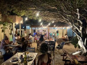 a group of people sitting at tables at a restaurant at night at Pousada Vila Matury in Icapuí