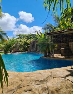 a pool in a resort with palm trees at Suítes House Refúgio Fortim in Fortim