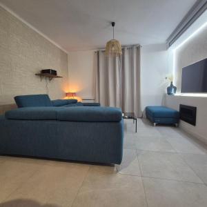 a living room with a blue couch and a television at LoveRoom La Parenthèse Secrète in Lampaul-Plouarzel