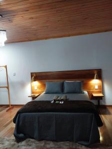 a bedroom with a large bed with a wooden headboard at Chalé Vila do Vento in Lavras Novas