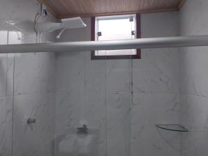 a bathroom with a shower with a sink and a window at Chalé Vila do Vento in Lavras Novas
