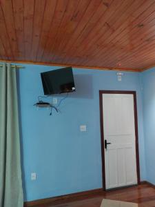 a room with a blue wall with a flat screen tv on a ceiling at Chalé Vila do Vento in Lavras Novas