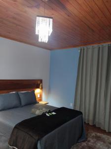 a bedroom with a bed and a chandelier at Chalé Vila do Vento in Lavras Novas +11 photos