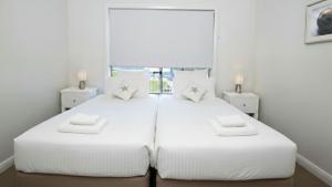 a bedroom with two beds with white sheets and pillows at Surf Mist in Gerroa