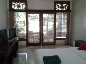 a bedroom with a bed and a tv and windows at Hotel SeaSide lovina in Lovina