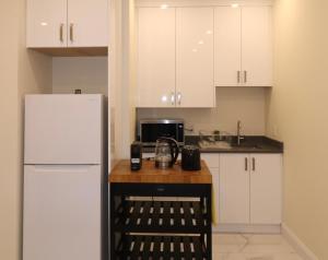 a kitchen with white cabinets and a white refrigerator at SixPine - One bedroom suite in Vancouver