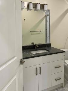 a white bathroom with a sink and a mirror at SixPine - One bedroom suite in Vancouver +2 photos