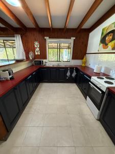 a kitchen with black cabinets and red counter tops at Terrigal Cottage in Terrigal
