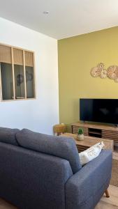 a living room with a blue couch and a tv at Casa Sole in Saint-Chamond