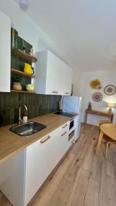 a kitchen with white cabinets and a sink and a table at Casa Sole in Saint-Chamond