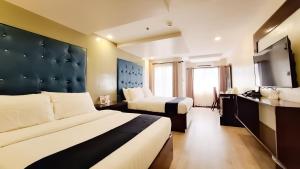 ein Hotelzimmer mit zwei Betten und einem Fernseher in der Unterkunft ECL Resort Hotel Boracay in Boracay