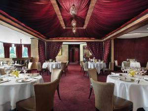 een eetkamer met witte tafels en stoelen en rode tapijt bij The Langham Hong Kong in Hong Kong