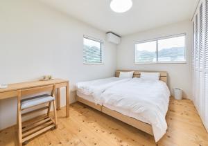 a bedroom with a bed and a desk and two windows at Cortile in Mitoyo