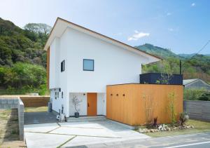 a white house with a brown fence at Cortile in Mitoyo