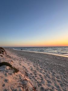 a beach at sunset with people walking in the water at The Seaview at Semaphore Park in Port Adelaide