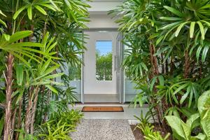 a hallway with palm trees in a house at Deja View Trinity Beach in Trinity Beach