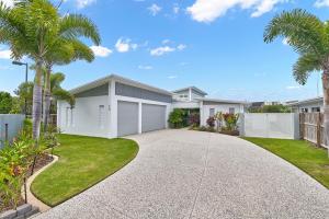 a house with a driveway and palm trees at Deja View Trinity Beach in Trinity Beach