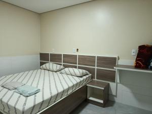 a small bedroom with a bed with a wooden headboard at Hotel cowboy Interlagos próximo do autódromo e transamérica Expo Center in São Paulo