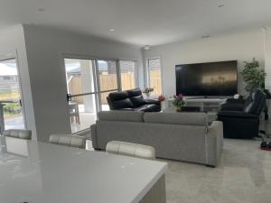 a living room with couches and a flat screen tv at Ensuite room in Mount Duneed in Mount Duneed