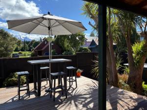 a patio with an umbrella and a table and stools at Ridley Manor in Ohakune