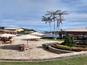 a patio with tables and umbrellas and the ocean at Flat Villas do Pratagy: Tranquilidade e Natureza ao Norte de Maceió in Maceió
