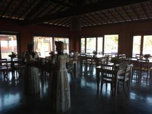 two women in dresses in a room with tables and chairs at Flat Villas do Pratagy: Tranquilidade e Natureza ao Norte de Maceió in Maceió