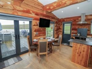 a dining room with a table and chairs and a television at Cedar Cabin at Salford Court Farm Fishing Cabins in Worcester