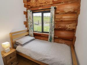 a small bed in a room with a window at Cedar Cabin at Salford Court Farm Fishing Cabins in Worcester