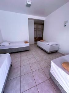a room with two beds and a tiled floor at Pousada luz do Sol in Cacoal