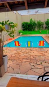 three chairs sitting next to a swimming pool at Pousada luz do Sol in Cacoal