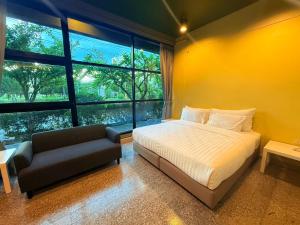 a bedroom with a bed and a couch and windows at Work Den Chiangrai in Chiang Rai