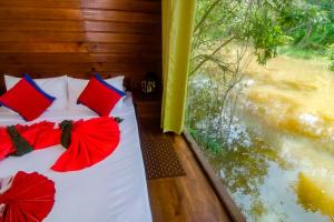 a bedroom with a bed with red pillows and a window at Harmony by the lake in Dambulla