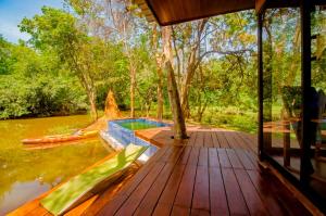 a wooden deck with a swimming pool next to a river at Harmony by the lake in Dambulla