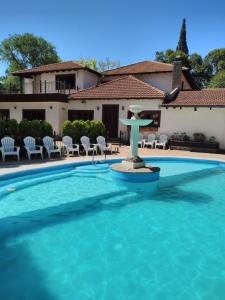 a pool with a fountain in front of a house at Rancho Grande Hotel in Villa General Belgrano