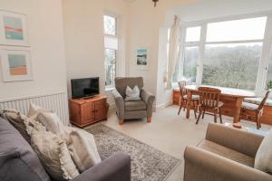 a living room with a couch and a tv and a table at 1 Hazeldene in Salcombe