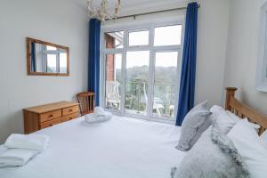 a bedroom with a white bed and a large window at 1 Hazeldene in Salcombe