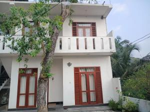 a white house with red doors and a tree at The Grand Villa Malabe in Malabe