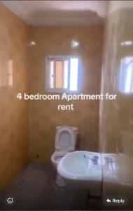 a bathroom with a white toilet and a sink at BUSUBALA Resident in Yundum