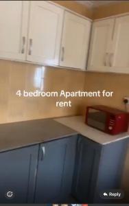a kitchen counter with white cabinets and a microwave at BUSUBALA Resident in Yundum