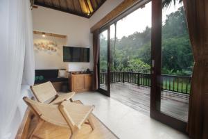 a living room with a balcony with a sliding glass door at The Tirta Sari Villas in Tegalalang