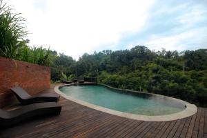 a swimming pool on top of a wooden deck at The Tirta Sari Villas in Tegalalang