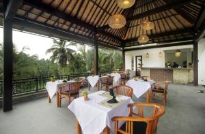 a restaurant with white tables and chairs and a balcony at The Tirta Sari Villas in Tegalalang