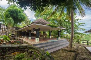 a house with a porch with stairs and palm trees at Wisma Belerang Kalianda Lampung RedPartner in Kalianda