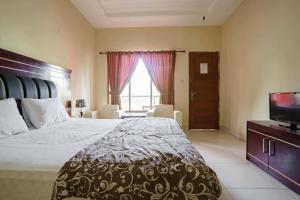 a bedroom with a large bed and a television at Wisma Belerang Kalianda Lampung RedPartner in Kalianda