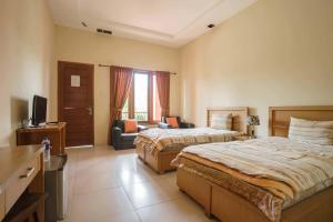 a hotel room with two beds and a television at Wisma Belerang Kalianda Lampung RedPartner in Kalianda +26 photos