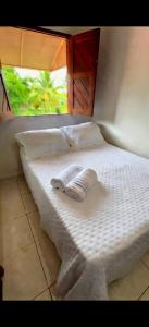 a white bed with two towels on top of it at Pousada Maresia do Sargi in Uruçuca
