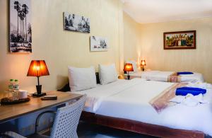 a hotel room with two beds and a desk and a bed at Villa Blue Lagoon in Sihanoukville