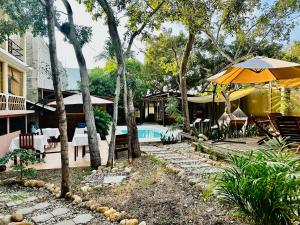 a backyard with a pool and a house with an umbrella at Suites Costa Madéro - Punta Zicatela in Brisas de Zicatela